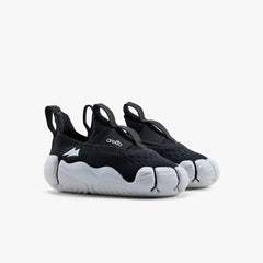 A pair of classic black Aretto kids' shoes with flexible white segmented soles, displayed side-by-side against a white background. (Sizes S1 & S2)