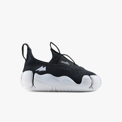 Side profile view of a single Aretto kids' shoe, highlighting the classic black knit upper and ergonomic contrasting white sole. (Sizes S1 & S2)
