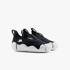 A pair of classic black Aretto kids' shoes with flexible white segmented soles, displayed side-by-side against a white background. (Sizes S3 & S4)