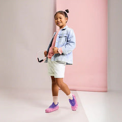Young girl wearing Aretto Leaps Pixl pink and purple kids sneakers with a denim jacket and white shorts. S1 & S2